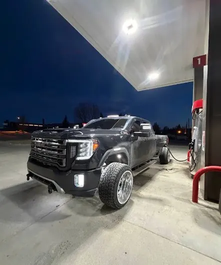Black GMC dually at night at a fuel station
